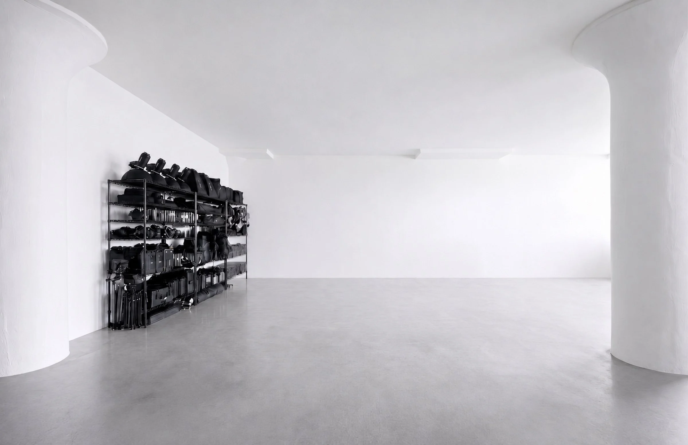 The empty shooting floor: polished concrete, two round white columns and lighting gear on wire shelves