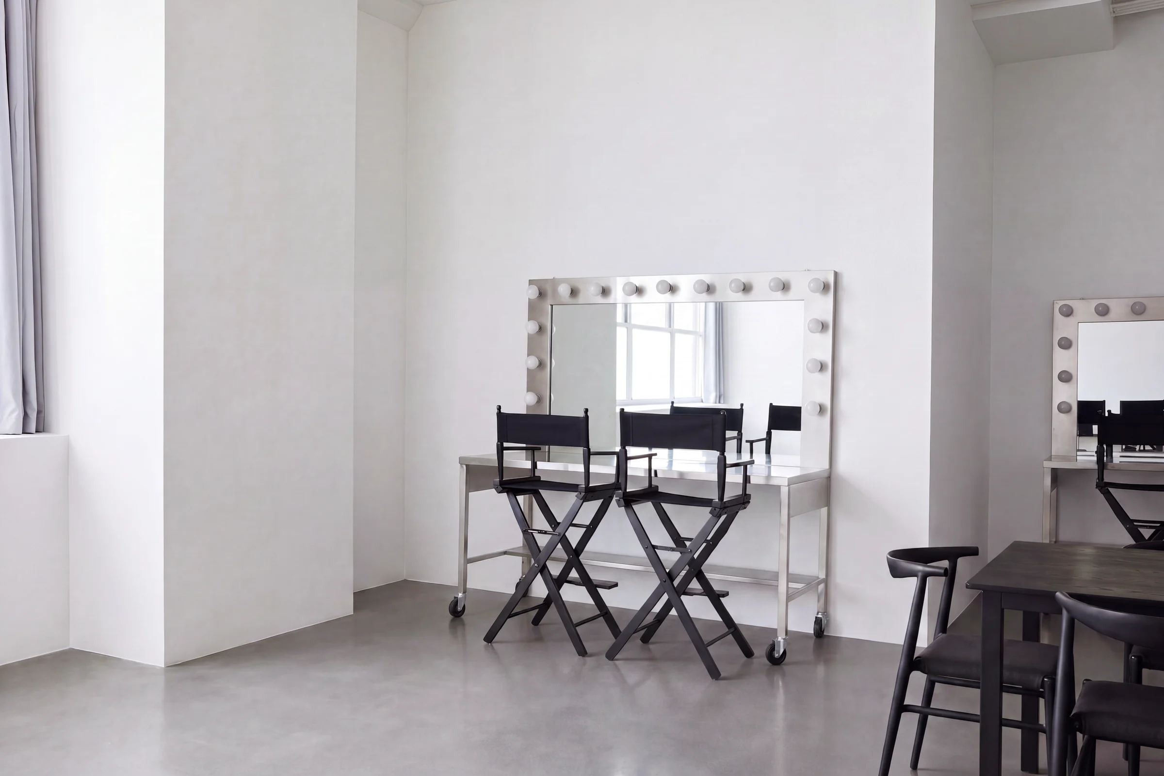 A makeup station with lit mirrors and two director's chairs