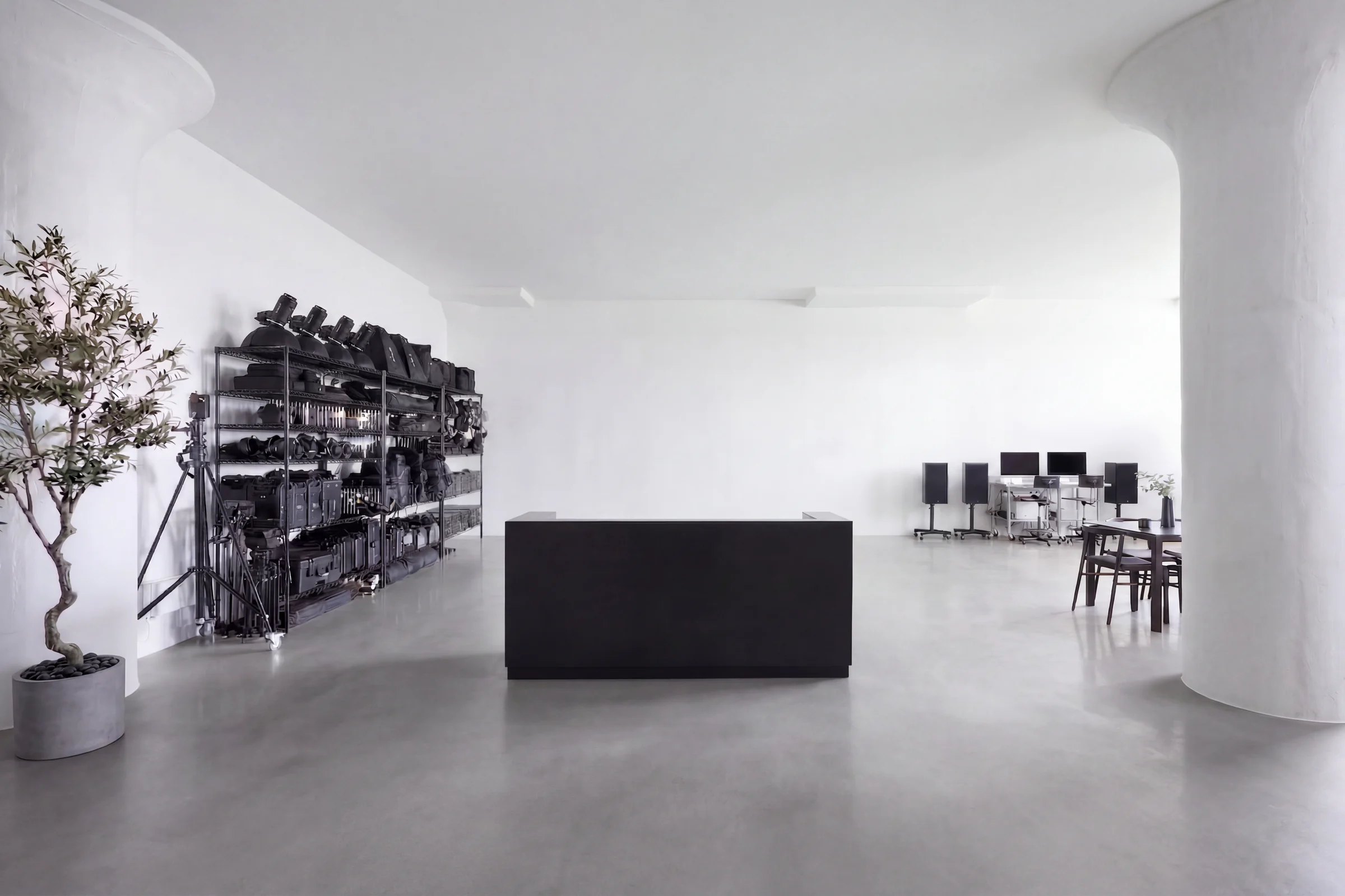 Grip and lighting equipment on shelves behind a black counter, between two round columns
